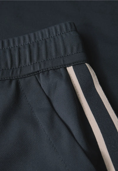 Close-up of dark pants with a beige stripe on a black background