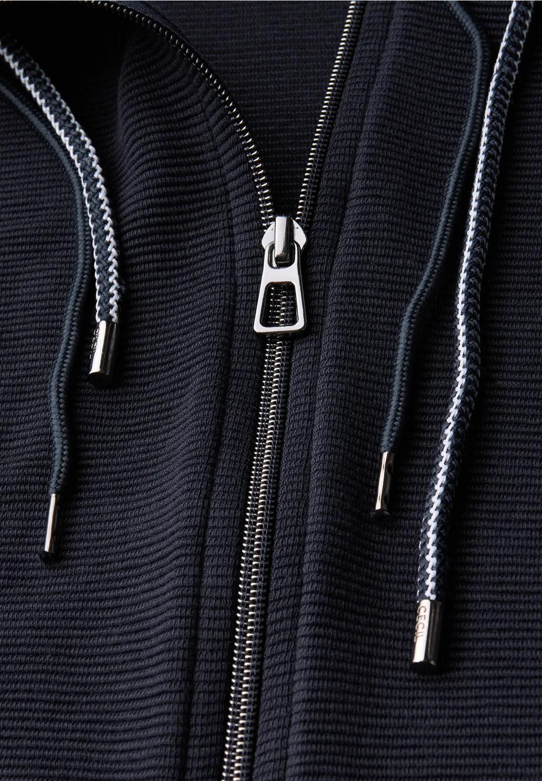 Close-up of a black textured hoodie with a zipper