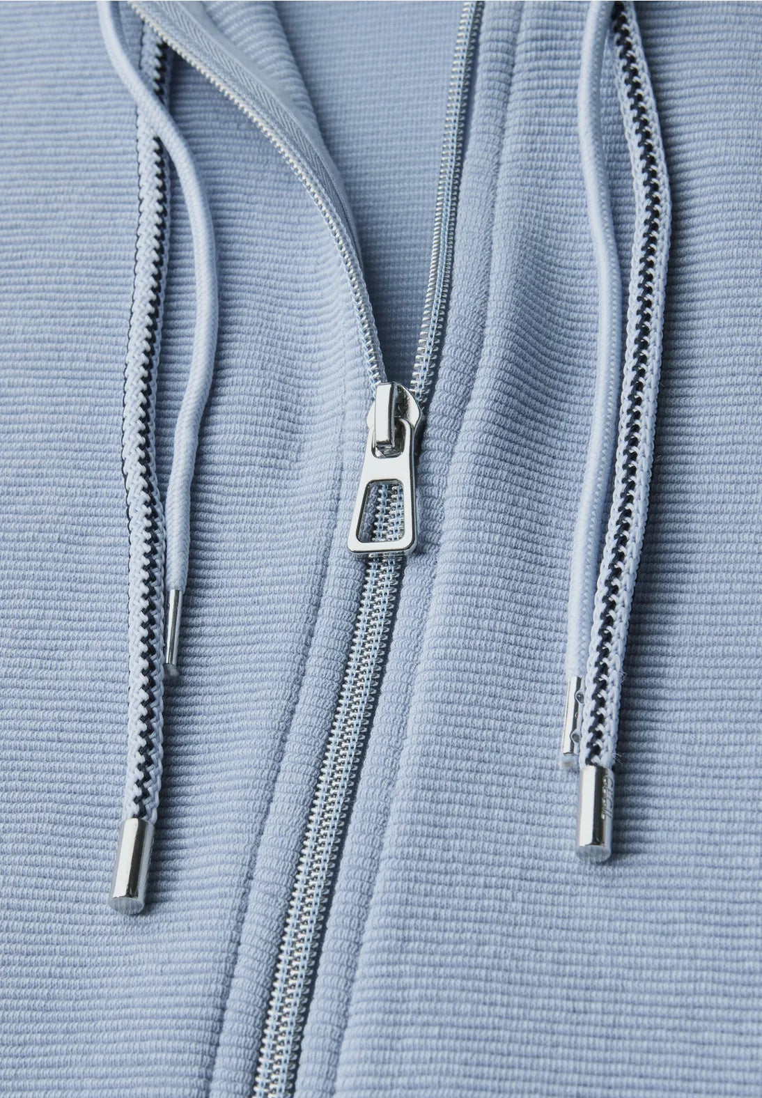 Close-up of a blue textured fabric with a zipper and drawstrings.