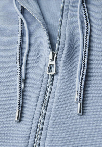 Close-up of a blue textured fabric with a zipper and drawstrings.