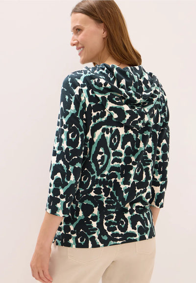 Woman wearing a patterned top with a neutral background