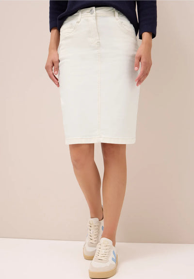 Person wearing a white denim skirt with a plain background