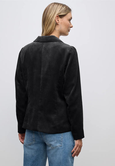 Person wearing a black jacket and blue jeans on a plain background