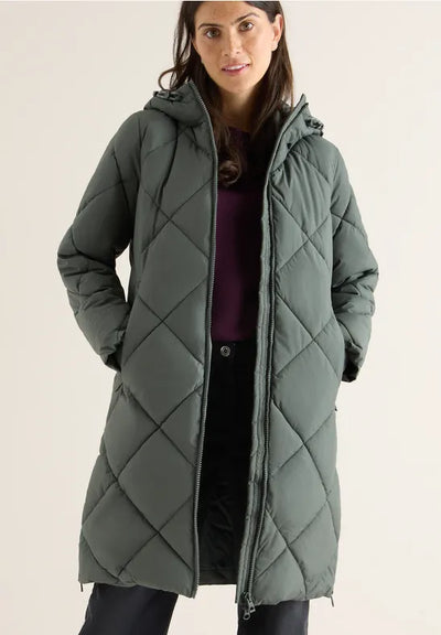 Woman wearing a long quilted green coat on a plain background