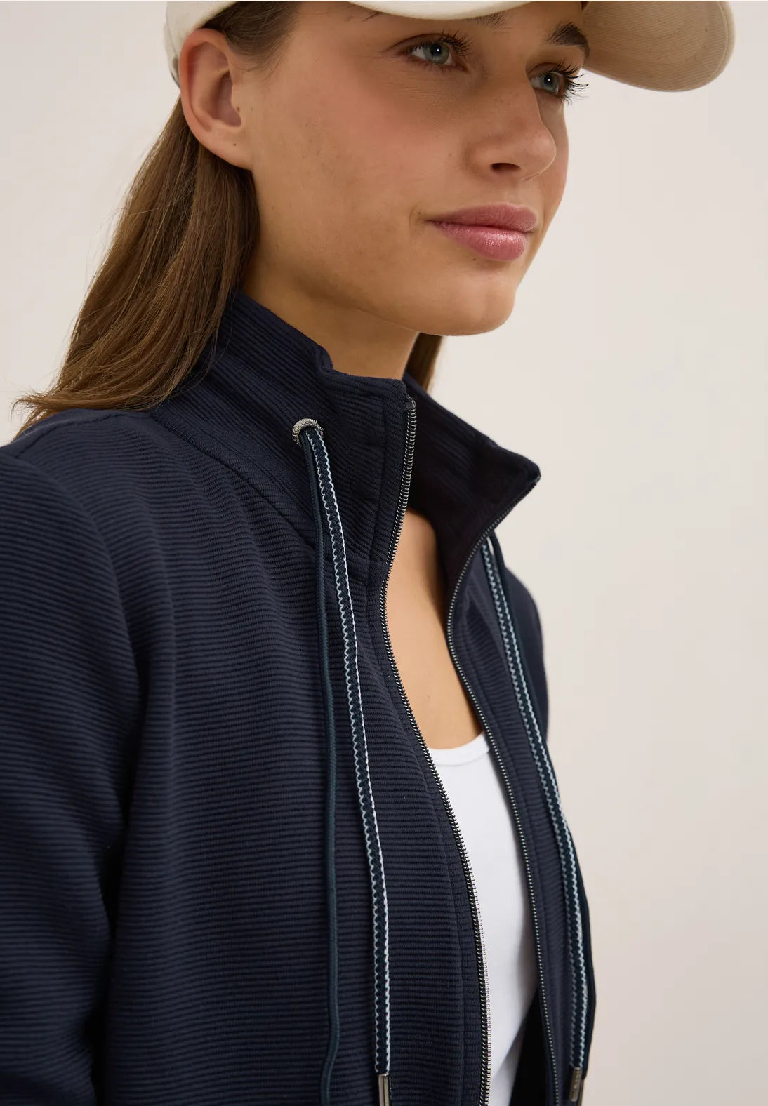 Woman wearing a navy jacket with a white background
