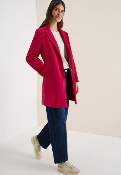 Woman wearing a red coat with a plain background