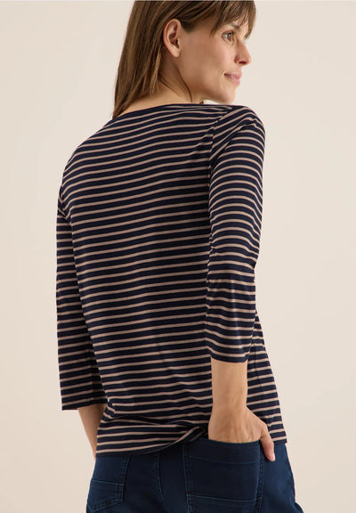 Woman wearing a black and beige striped long-sleeve shirt against a beige background