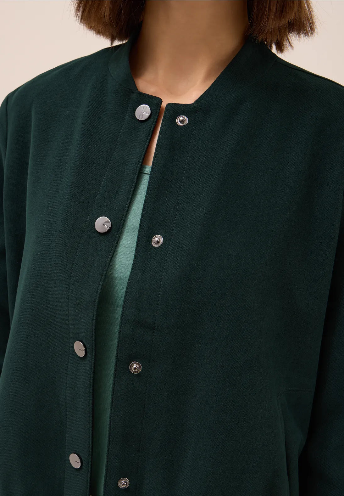 Close-up of a dark green jacket with buttons on a neutral background