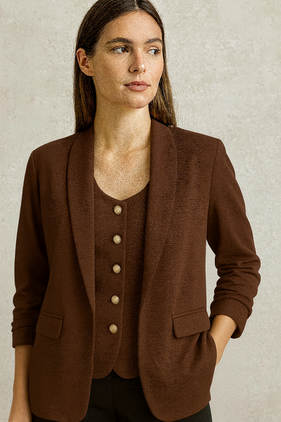 Woman wearing a brown blazer with a neutral background