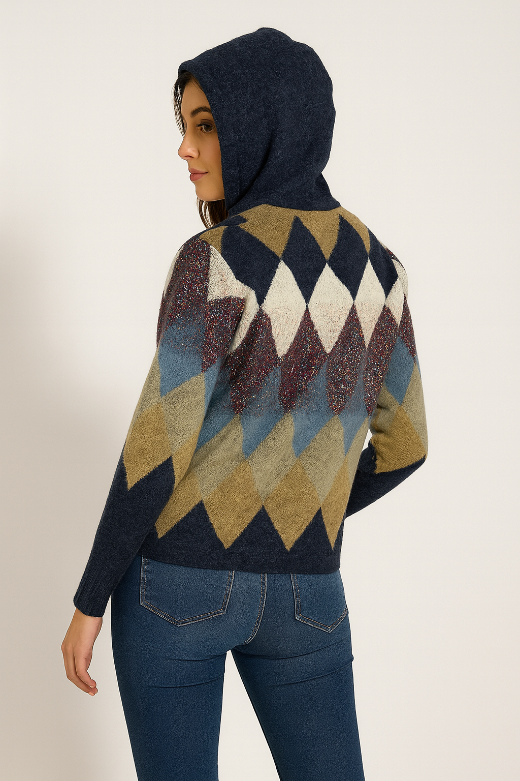 Person wearing a patterned sweater with a hood on a plain background