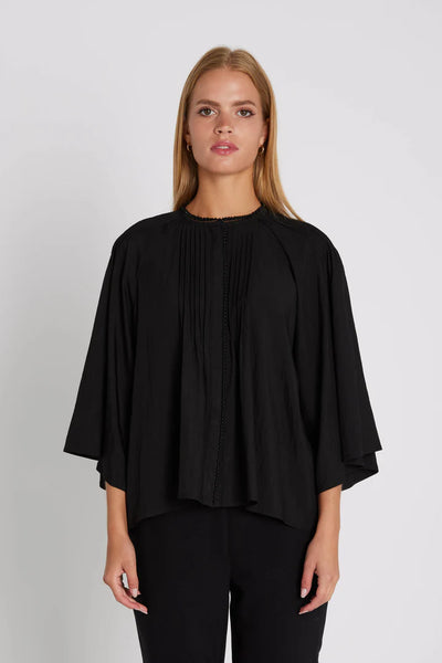 Woman wearing a black blouse with a plain background