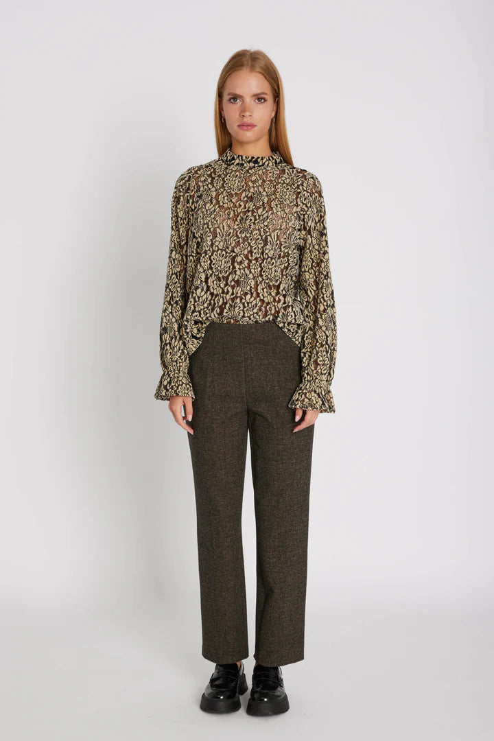 Woman wearing a patterned blouse and brown pants on a white background
