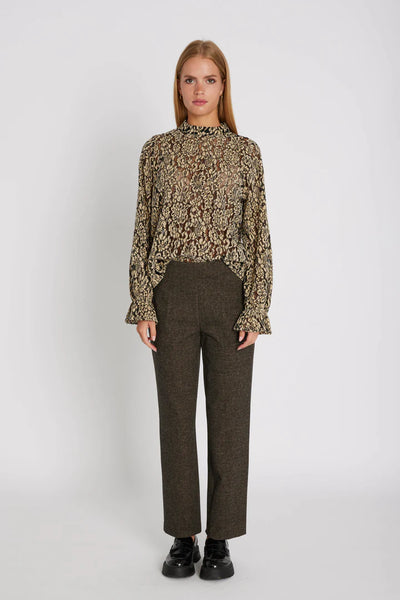 Woman wearing a patterned blouse and brown pants on a white background