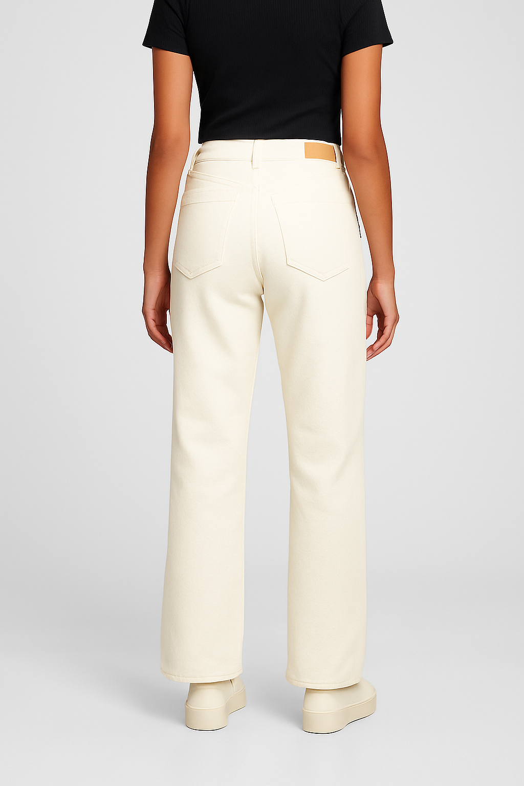 Person wearing beige pants and a black top on a light gray background