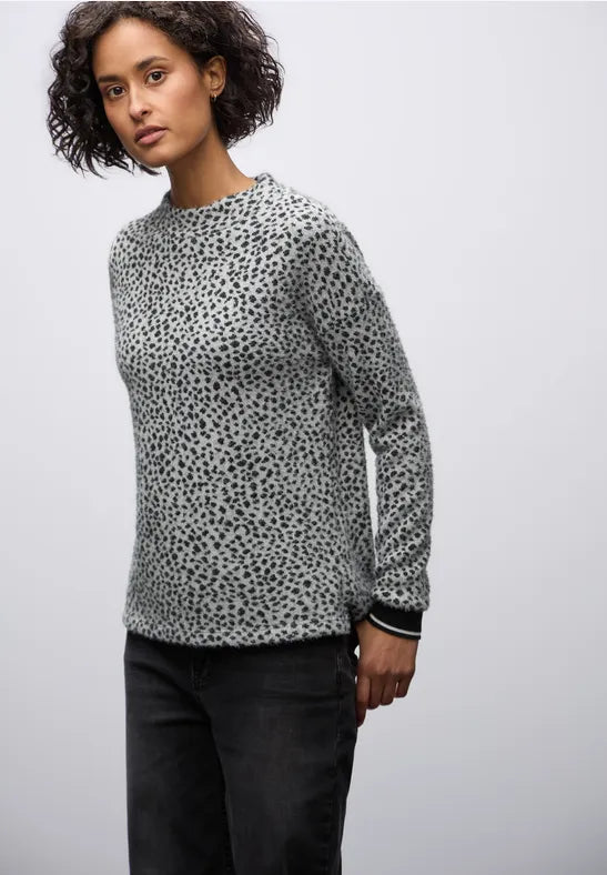 Person wearing a patterned sweater against a plain background