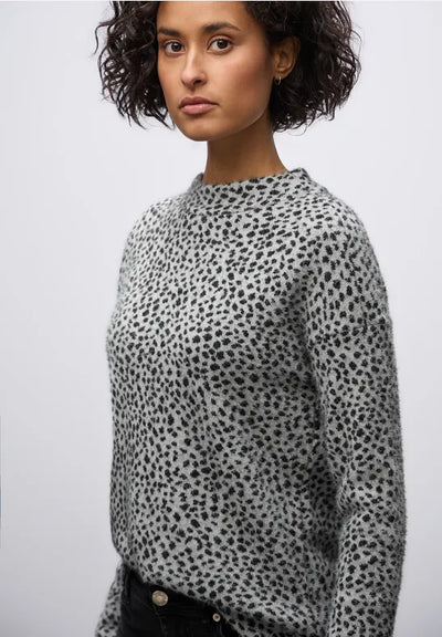 Woman wearing a patterned sweater against a plain background