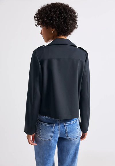 Person wearing a black jacket and blue jeans on a white background