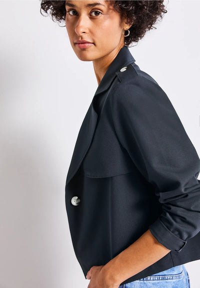 Woman wearing a black jacket with silver buttons on a white background
