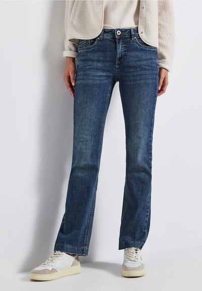 Person wearing blue jeans and a light-colored shirt on a plain background