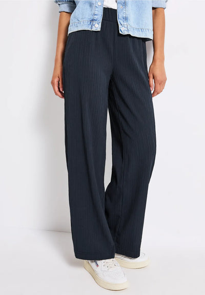 Person wearing black pinstripe pants with a light blue denim jacket on a white background
