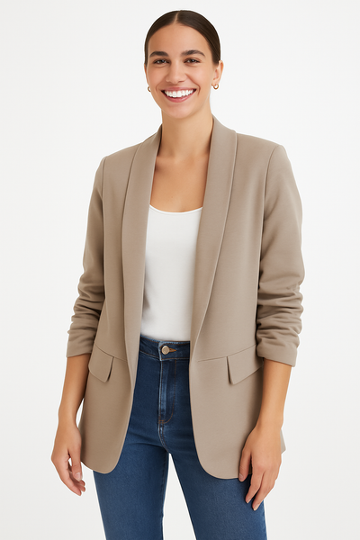 Woman wearing a beige blazer over a white top and blue jeans on a white background
