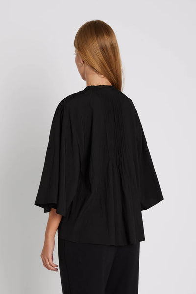 Person wearing a black outfit with a plain background