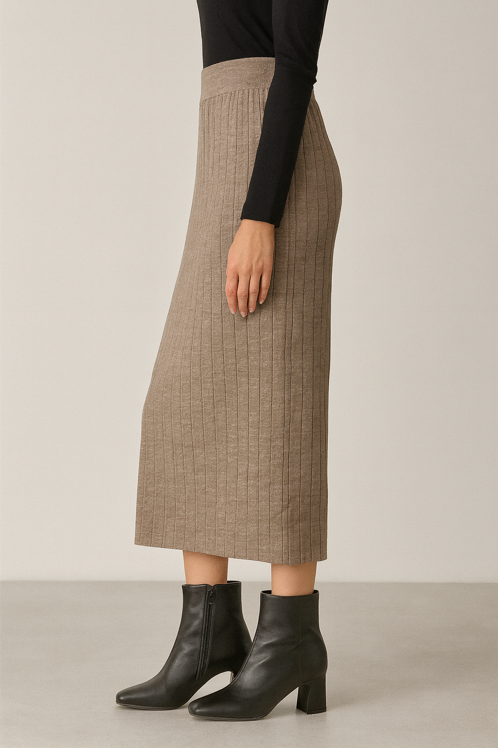Person wearing a beige plaid skirt and black boots on a plain background