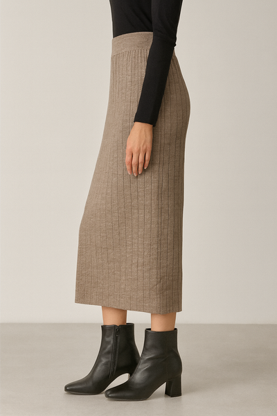 Person wearing a beige plaid skirt and black boots on a plain background