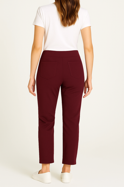 Person wearing burgundy pants and a white top on a plain background