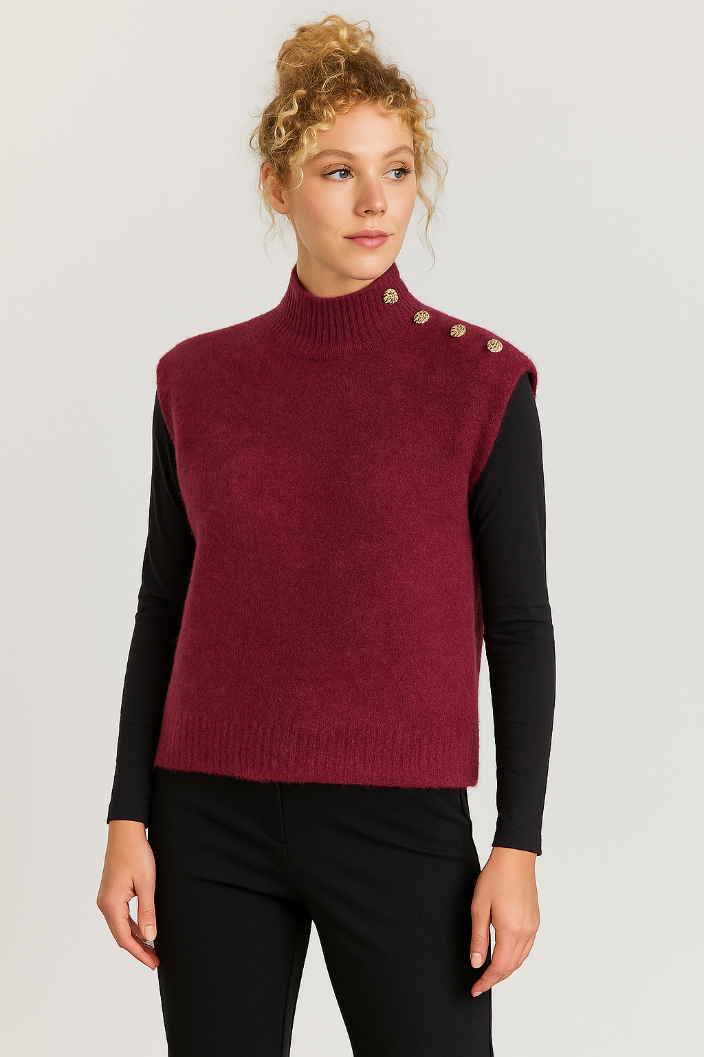 Woman wearing a burgundy sweater vest with button details on a plain background