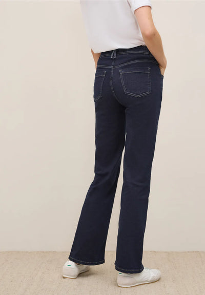 Person wearing dark blue jeans on a plain background