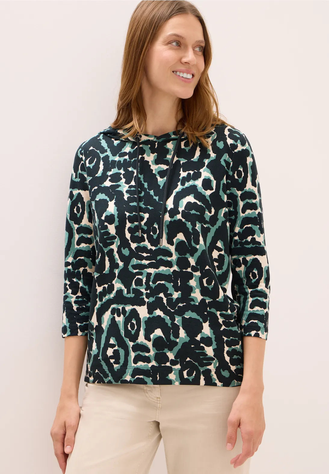 Woman wearing a patterned top with a plain background