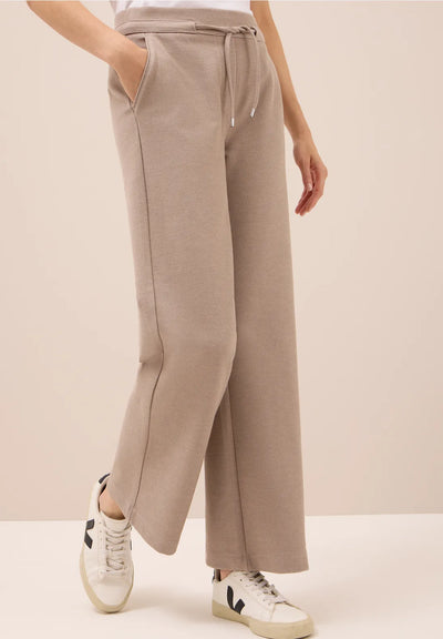 Beige wide-leg pants worn by a person on a beige background
