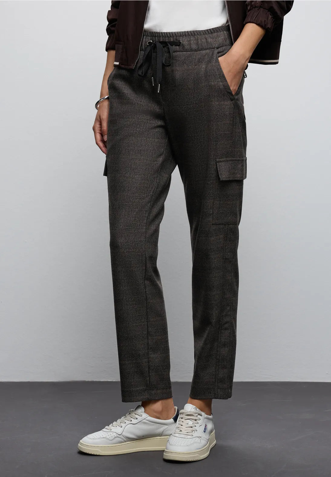 Person wearing dark gray cargo pants with a plain background