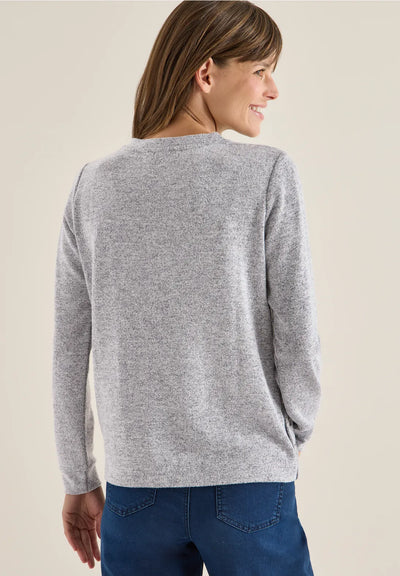 Woman wearing a gray sweater and blue jeans on a beige background