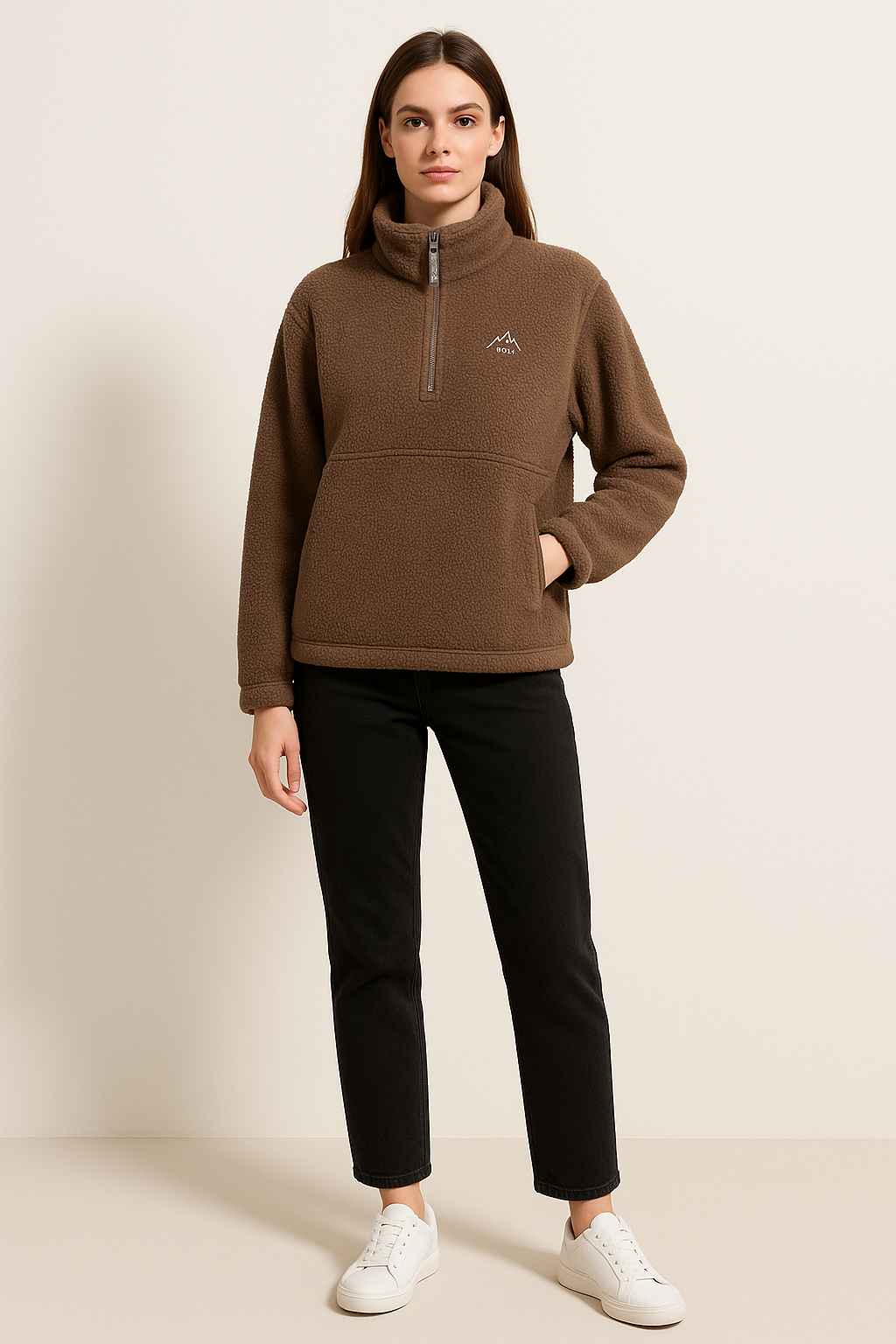 Woman wearing a brown fleece pullover with a logo on a beige background