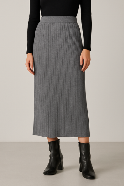 Person wearing a gray ribbed skirt with black boots on a neutral background