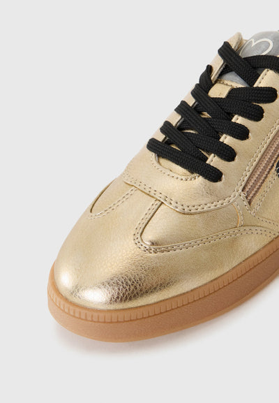 Gold sneaker with black laces on a white background