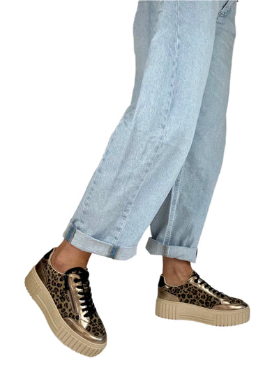 Leopard print sneakers worn with light blue jeans on a white background