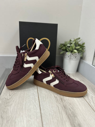 Pair of maroon sneakers with white zigzag pattern on a light wooden floor.