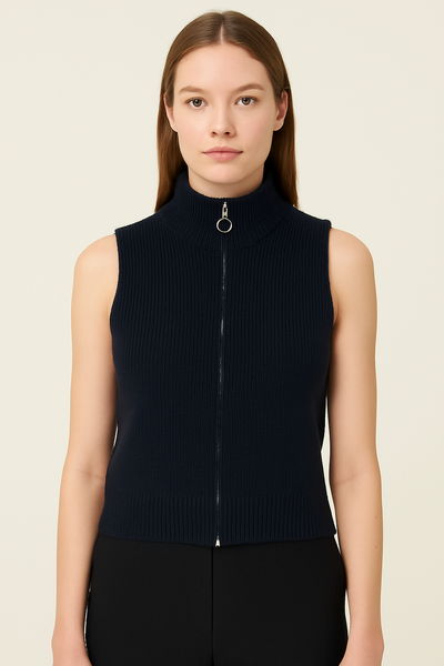 Woman wearing a black sleeveless zip-up sweater against a beige background