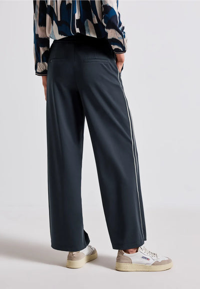 Person wearing dark gray wide-leg pants with a plain background