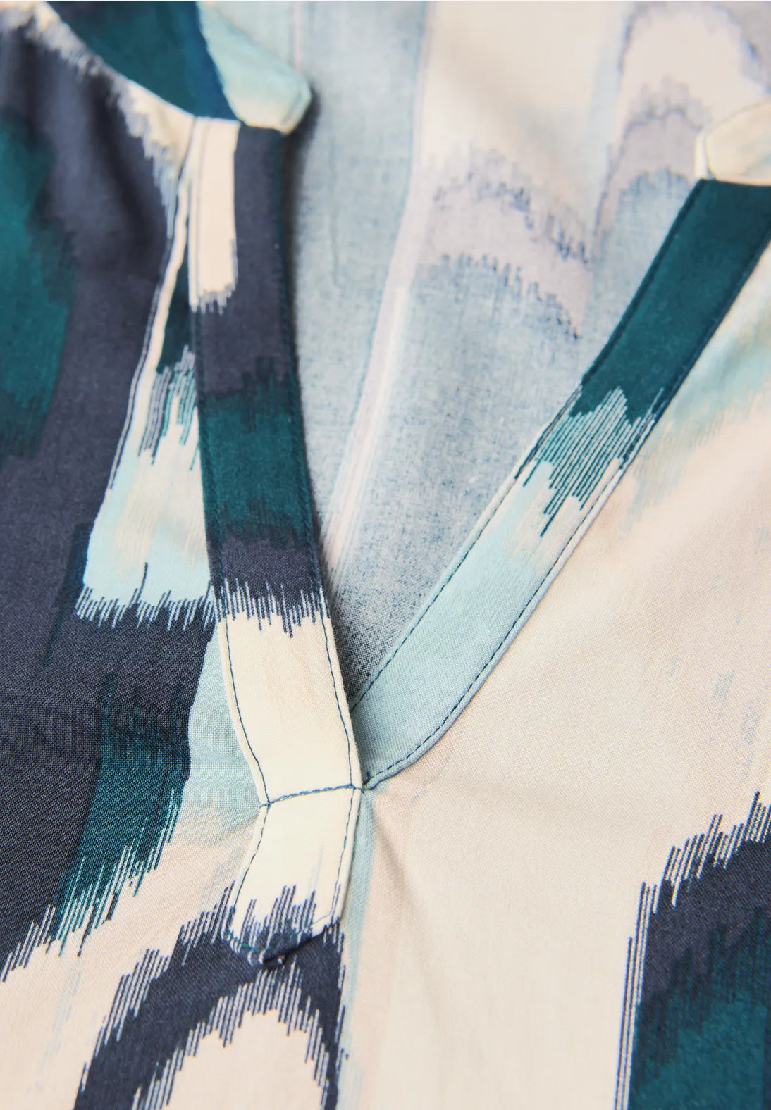 Close-up of a garment with geometric pattern in blue, green, and beige.