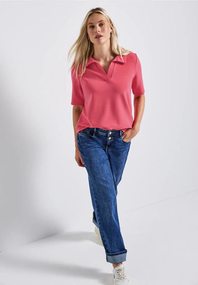 Woman wearing a pink polo shirt and blue jeans on a white background