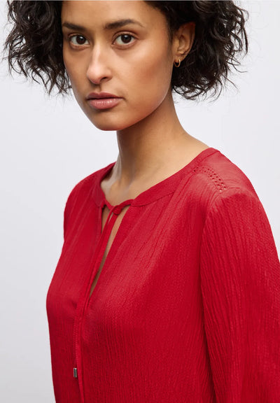 Woman wearing a red blouse against a plain background