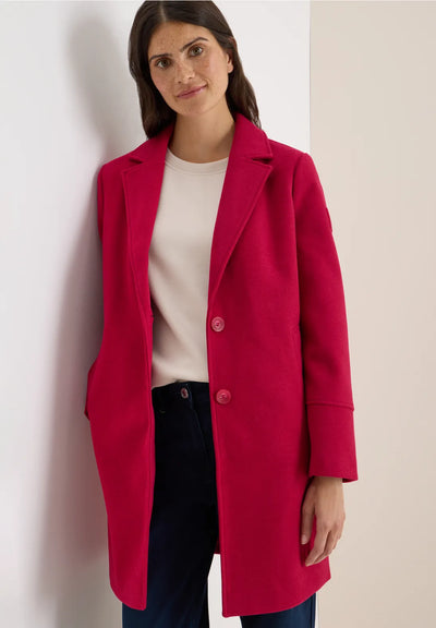 Woman wearing a red coat against a plain background