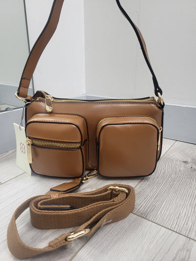 Brown leather handbag with a strap on a light wooden surface