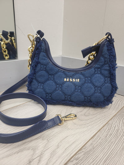 Blue textured dog harness with 'Bessie' branding on a light wooden surface.