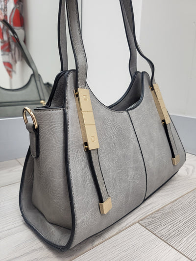 Gray handbag with gold accents on a light wooden surface