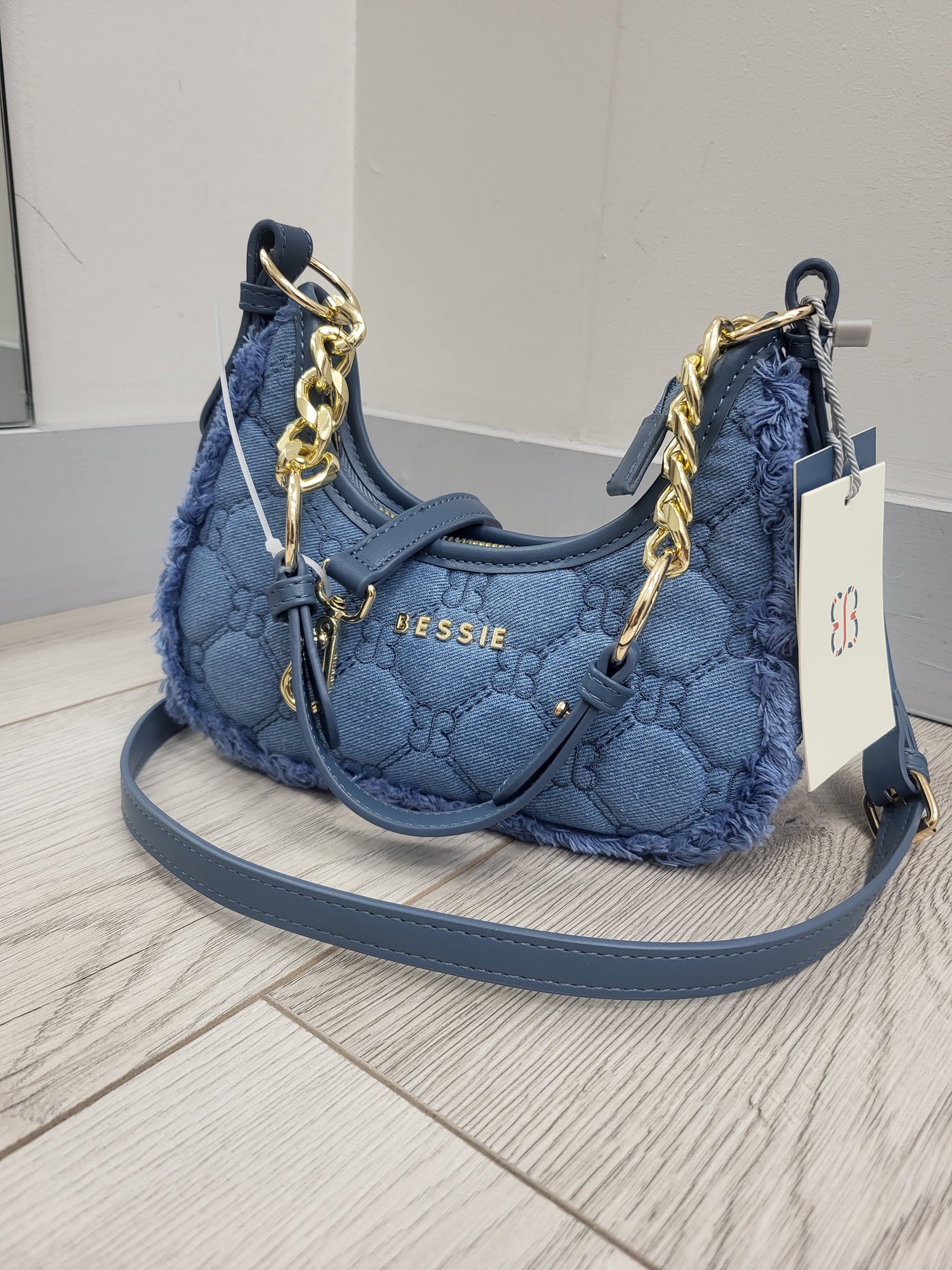 Blue handbag with gold chain detail on a light wooden floor